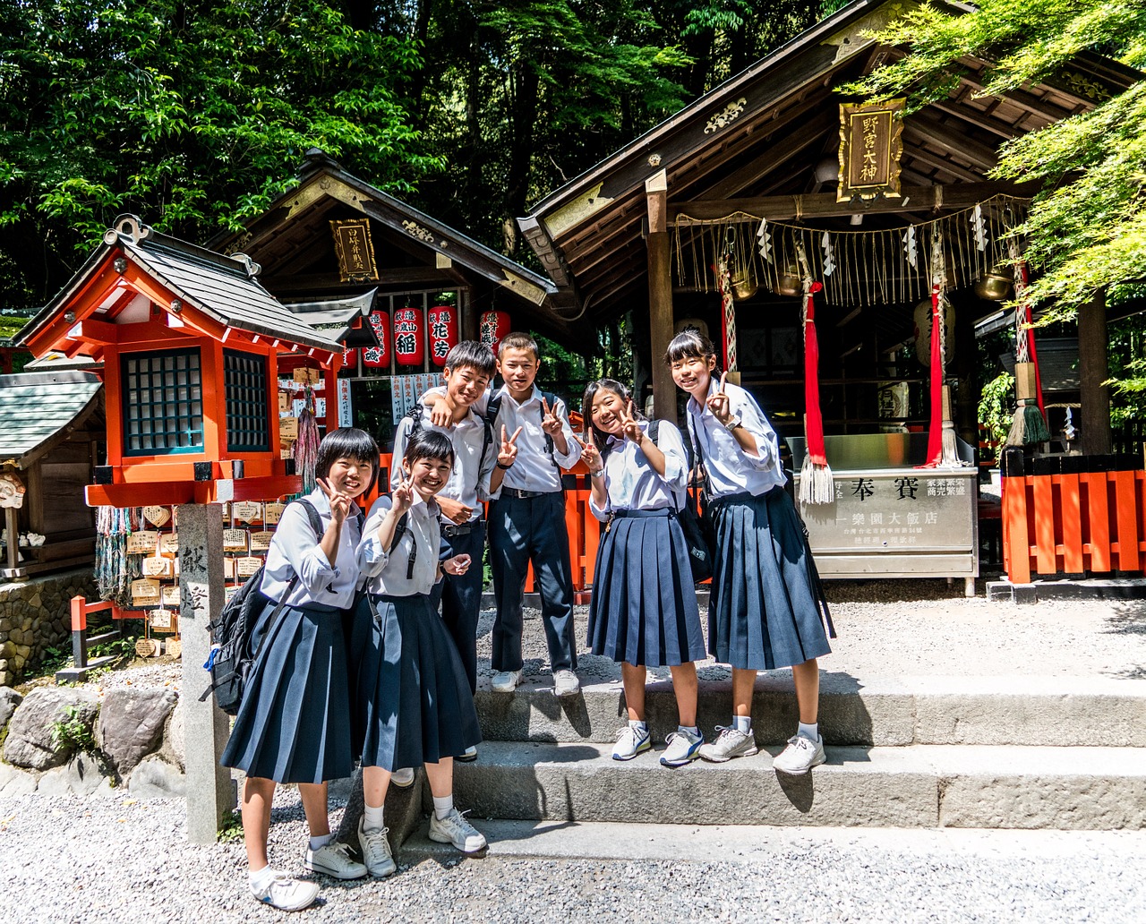 Six Japanese schoolchildren stand in front of a shrine